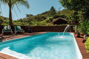 Relax by the serene pool surrounded by lush greenery and a soothing waterfall.