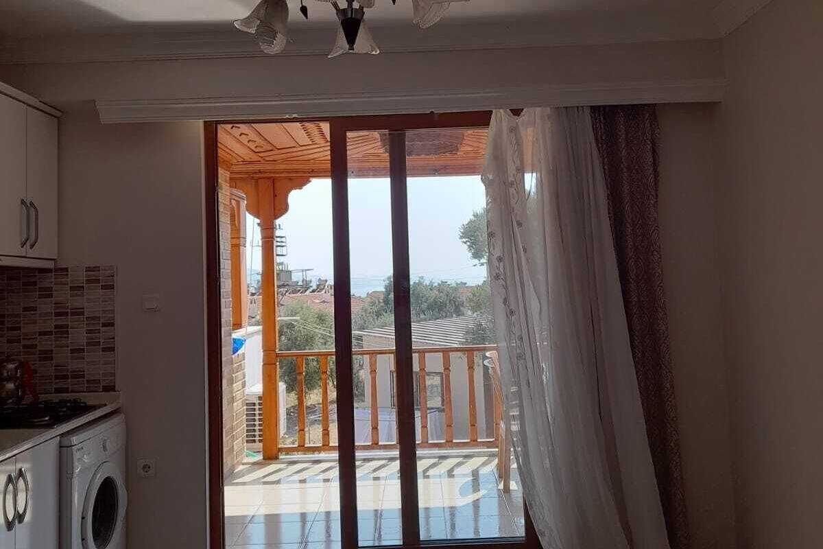 A kitchen with a washing machine, a ceiling fan, and a sliding glass door leading to an outdoor balcony.