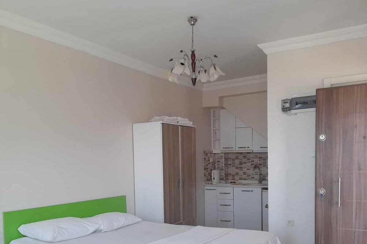 A bedroom with a bed, a wardrobe, a kitchenette, and a bathroom.