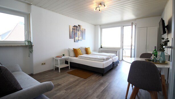 Un dormitorio moderno y bien iluminado, con cama, mesitas de noche y una ventana.