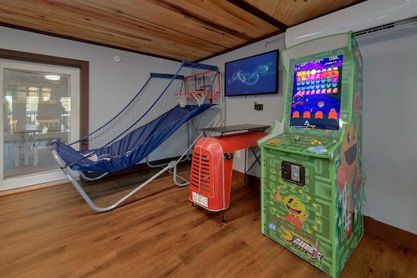 A room with a trampoline, a gaming console, and a basketball hoop.
