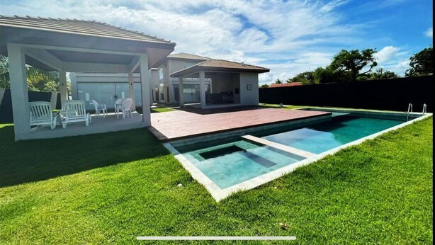 A modern house with a swimming pool, a covered patio, and a well-maintained lawn. - House with pool on the best beach in Itacimirim! (camaçari)