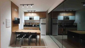 A modern kitchen with wooden cabinets, a central island, and a dining area with chairs. - House with pool on the best beach in Itacimirim! (camaçari)