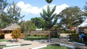 Un patio con una estructura de techo de paja, un área cercada y una zona de estar con una tienda de campaña.