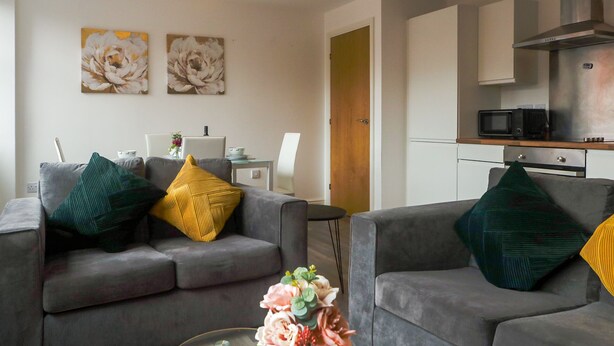 A modern living room with two grey sofas, a coffee table, and a vase of flowers.