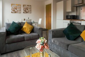 A modern living room with two grey sofas, a coffee table, and a vase of flowers.