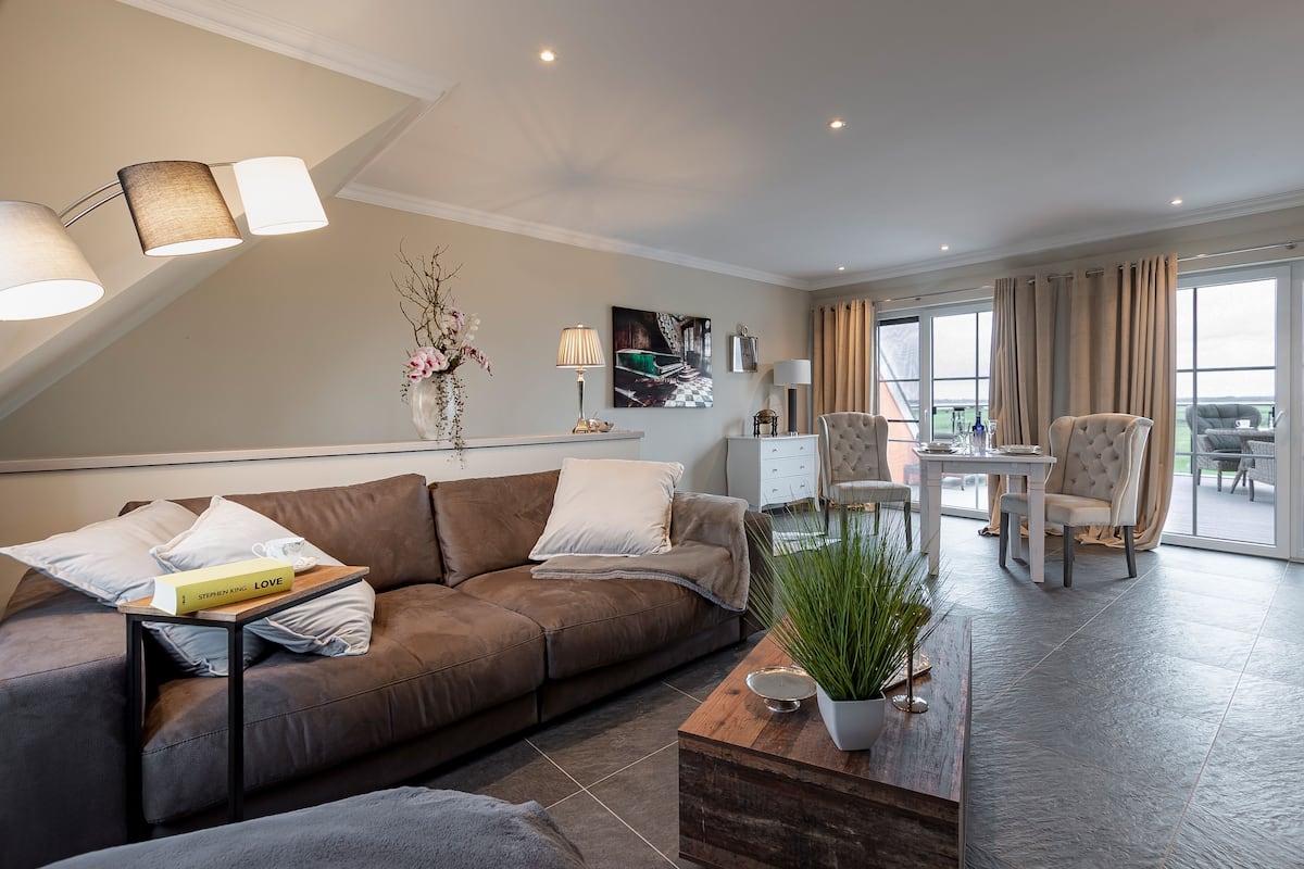A modern living room with a brown sofa, a coffee table, and a dining area with a table and chairs.
