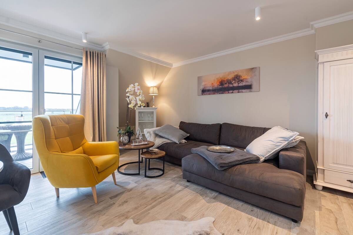 A modern living room with a sofa, armchair, and a small side table.