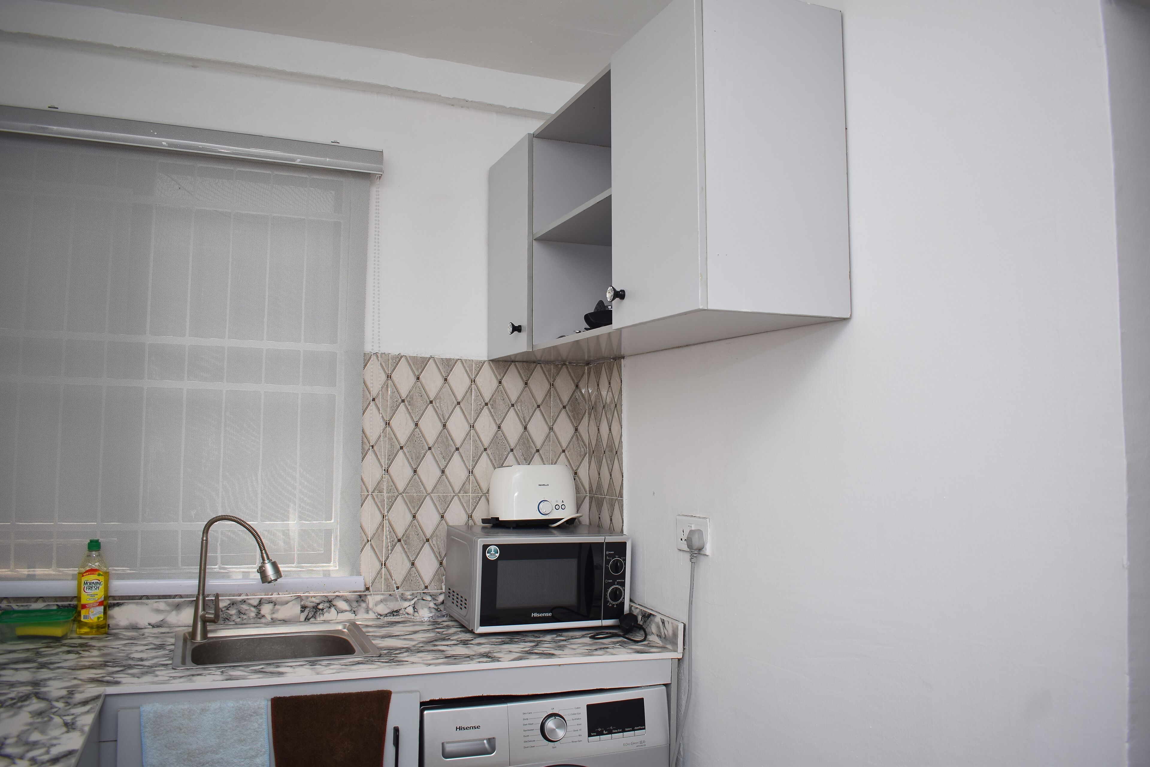 A compact kitchen with a sink, a microwave, and a toaster on the countertop.