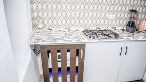 A kitchen with a gas stove, a coffee maker, and a trash bin. - Stunning 1-bed Apartment in Lekki Phase 1 (Lekki)
