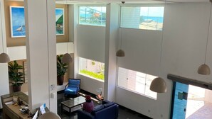 Tilava aula, jossa on vastaanottotiski, oleskelualue ja suuret ikkunat, joista avautuu näkymä ulos.