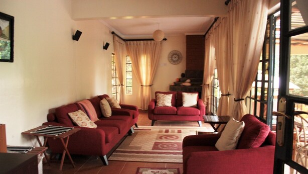 A living room with two red sofas, a small table, and a staircase leading to an upper level. - Tawa Country Lodge (Tawa)