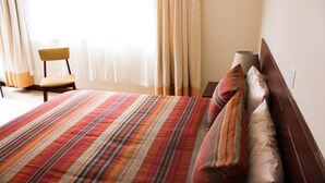 A hotel room with a large bed, a chair, and a lamp. - Tawa Country Lodge (Tawa)