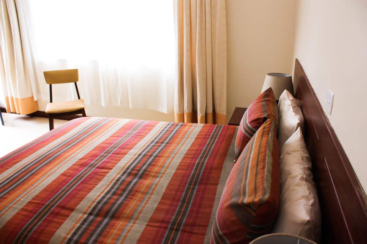 Una habitación de hotel con una cama grande, una silla y una lámpara.