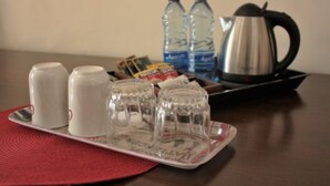A tray with salt and pepper shakers, two cups, two bottles of water, and a kettle on a table. - Tawa Country Lodge (Tawa)