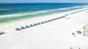 A beach with rows of umbrellas and lounge chairs, a sandy shore, and the ocean in the background. - Sea Oats 606 is a Gorgeous Gulf Front 3 BR - with Free Beach Service for 4 by RedAwning (Fort Walton Beach)