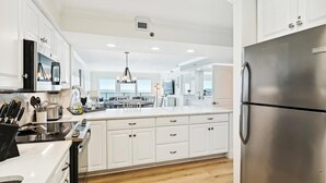 A modern kitchen with white cabinetry, stainless steel appliances, and a large island. - Sea Oats 606 is a Gorgeous Gulf Front 3 BR - with Free Beach Service for 4 by RedAwning (Fort Walton Beach)