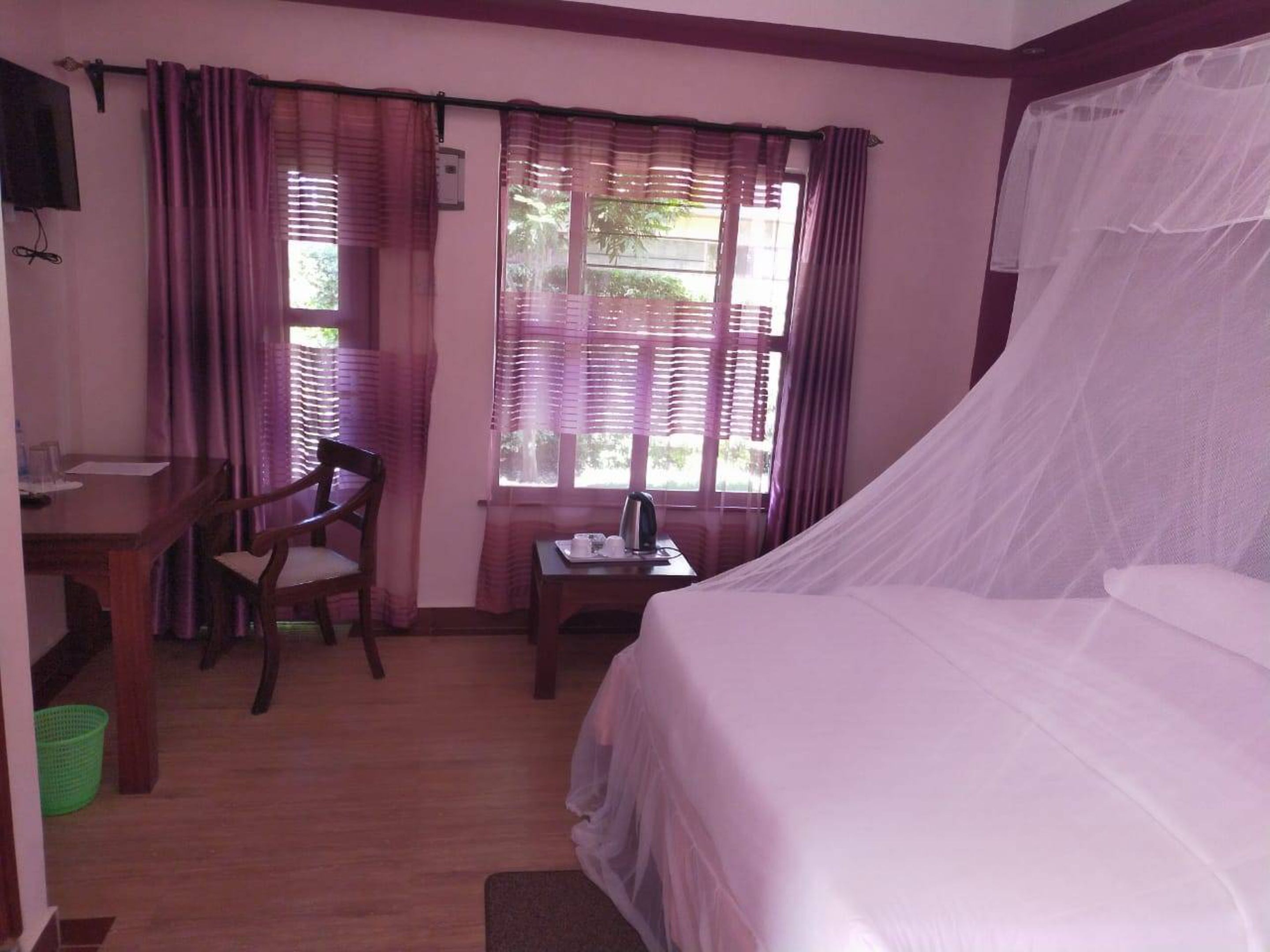 Ein Zimmer mit einem Bett, einem Schreibtisch, einem Stuhl und einem fenster mit Vorhängen.