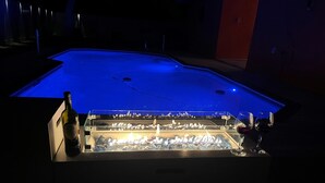 Uma área de bar com mesa de bilhar, uma garrafa de vinho e copos.
