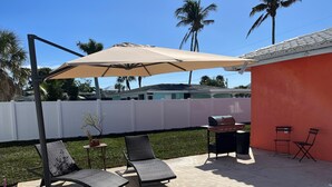 Um quintal com piscina, espreguiçadeiras, churrasqueira e um pergolado com cobertura.