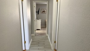 A hallway with a light-colored wooden floor and white walls. - Cozy, Licensed home, 15min from the strip. (Las Vegas)