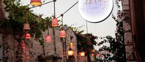 A rustic outdoor setting with hanging lanterns and a sign for ZETA.
