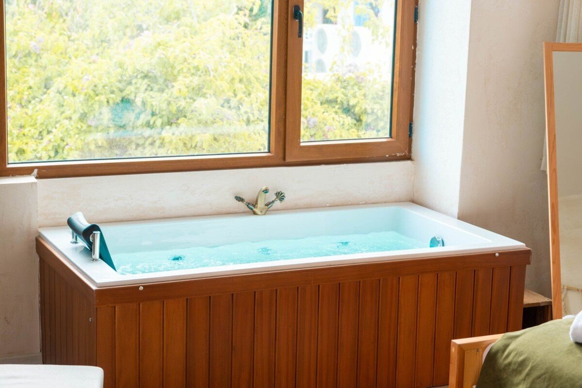Une baignoire en bois donnant sur un paysage verdoyant.