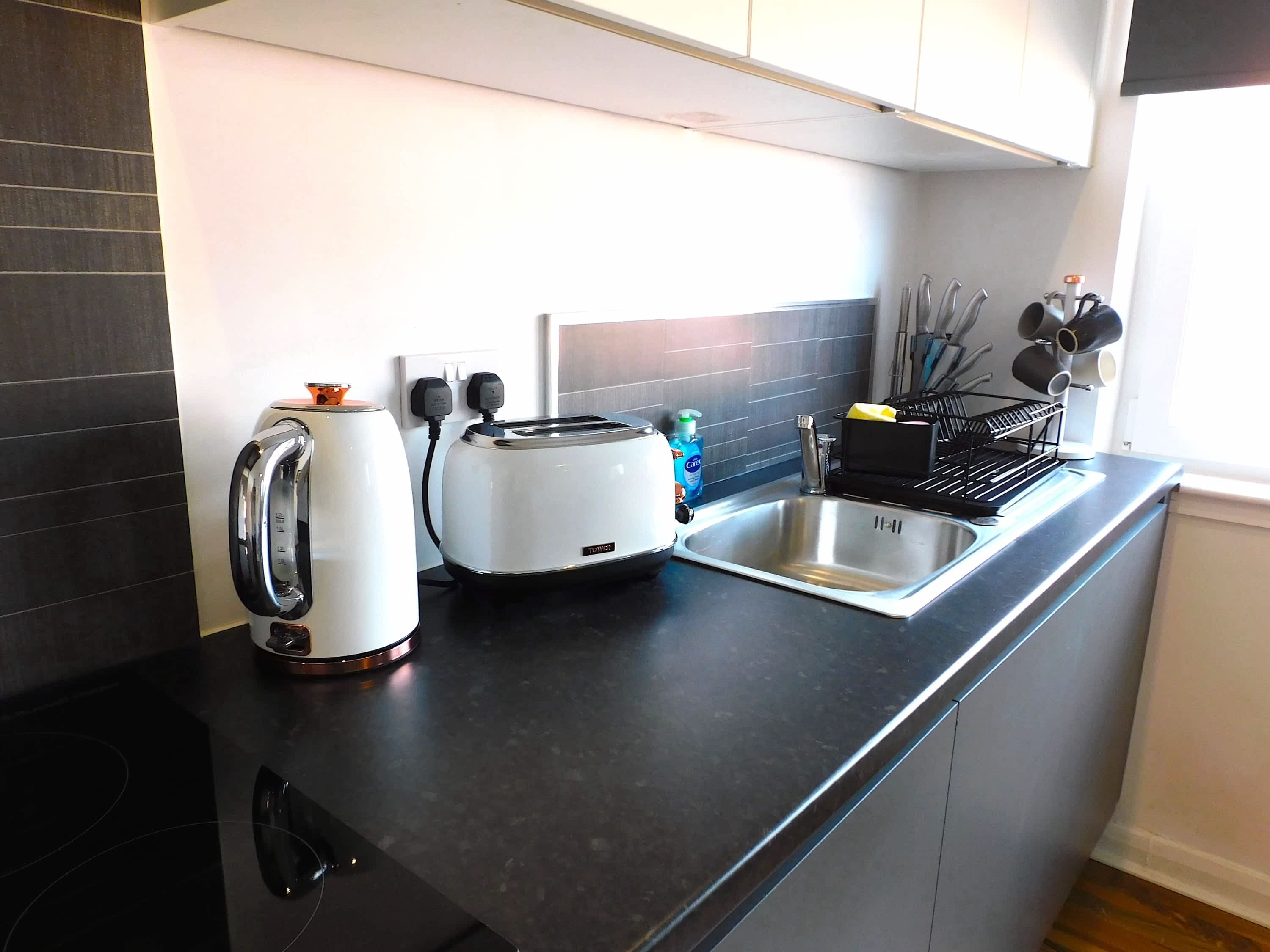 A modern kitchen with a toaster, kettle, and sink.