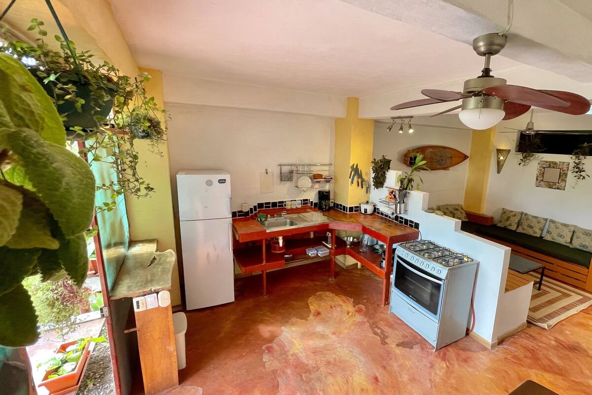 A compact kitchen with a refrigerator, stove, and a ceiling fan.