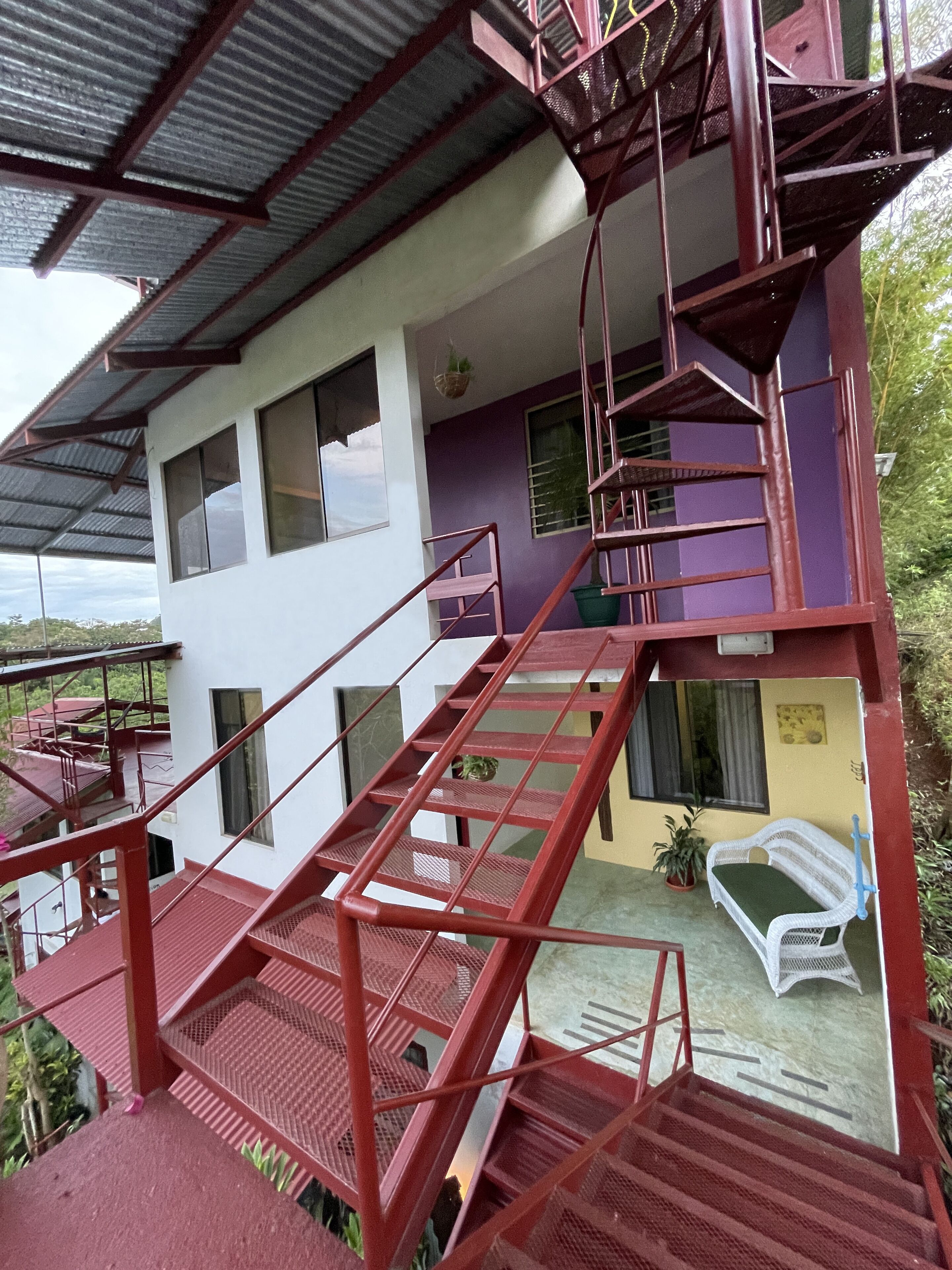 A multi-story building with a red staircase leading to a balcony.
