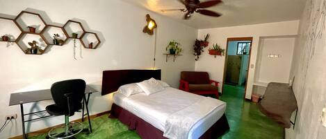 A bedroom with a bed, desk, chair, and a ceiling fan.