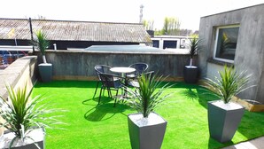 A rooftop patio with artificial grass, potted plants, and outdoor furniture. - Newly refurbished 2 bedroom apartment close to station and local amenities (Hamilton)