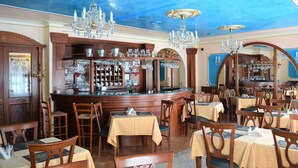 A restaurant with wooden furniture, chandeliers, and a bar area. - Renesance Krásná Královna (Karlovy Vary)