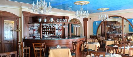 Un restaurante con mobiliario de madera, candelabros y una zona de bar.