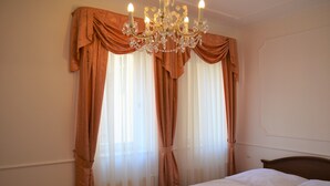 A hotel room with a bed, a chandelier, and curtains. - Renesance Krásná Královna (Karlovy Vary)