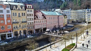 A riverside hotel with a stone bridge, multiple floors, and a pedestrian walkway. - Renesance Krásná Královna (Karlovy Vary)