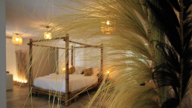 Una cama con dosel de madera, una mesita de noche y una lámpara.