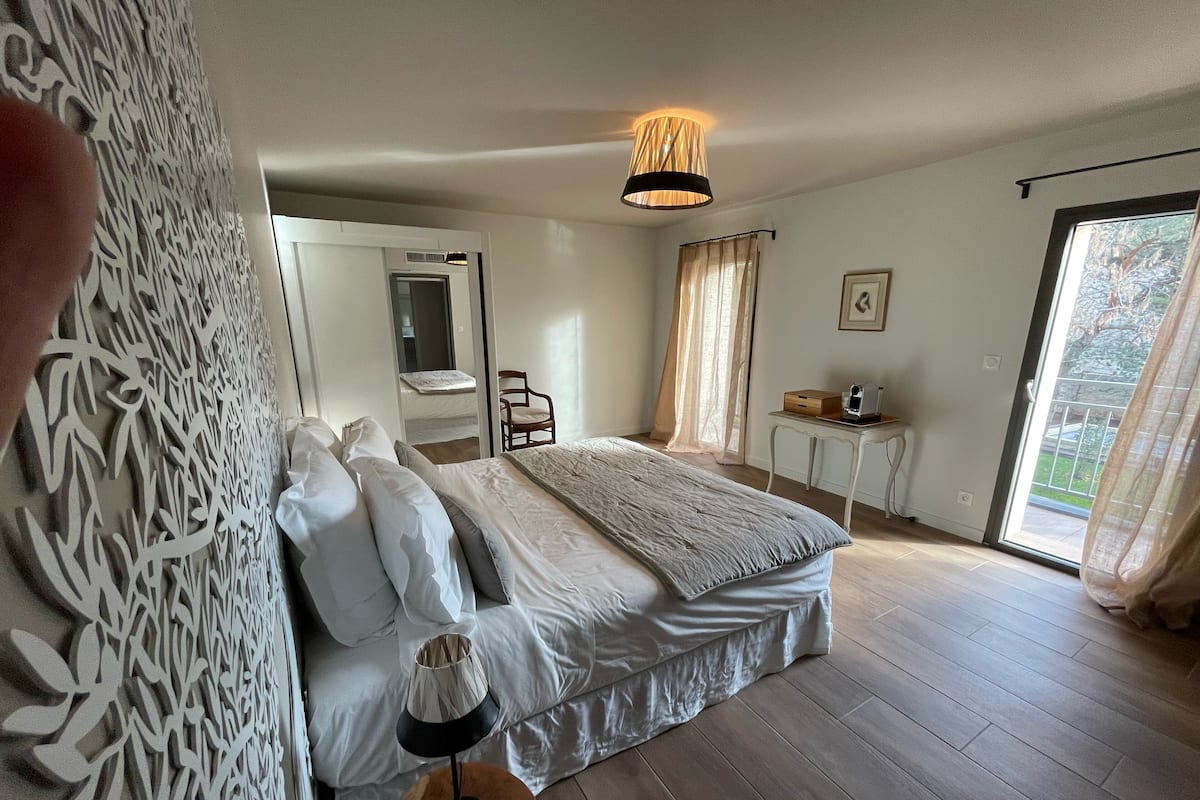A bedroom with a bed, a chair, a desk, and a window.