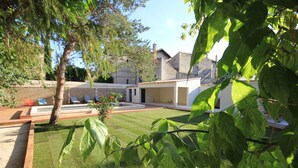 Un patio con césped, un árbol y un edificio con techo de tejas.