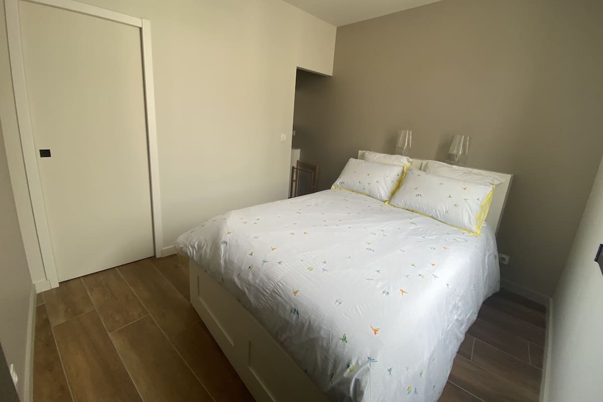 A bedroom with a bed, a door, and a light fixture.