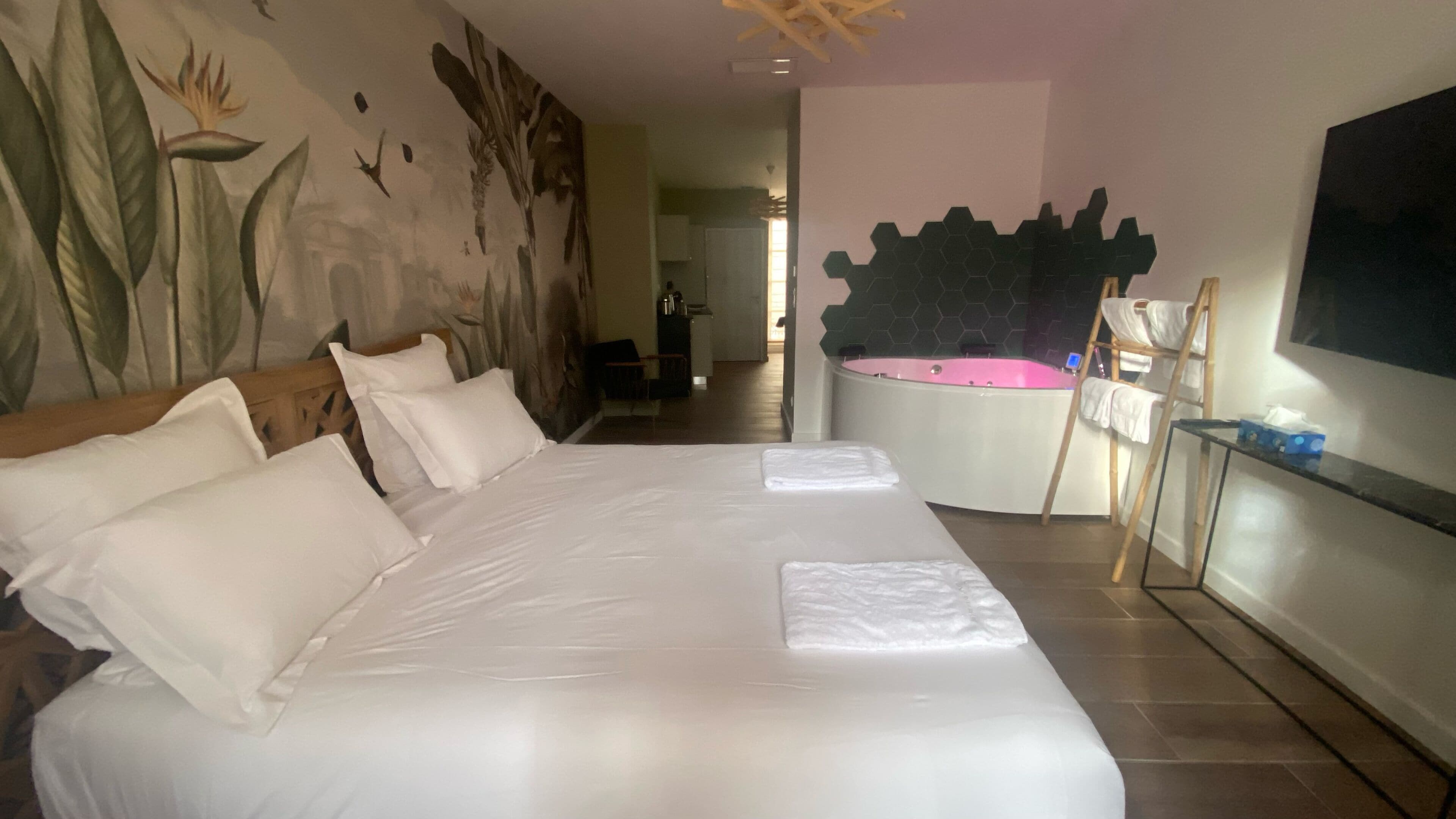 A large bed with white linens, a wooden headboard, and a painting on the wall.