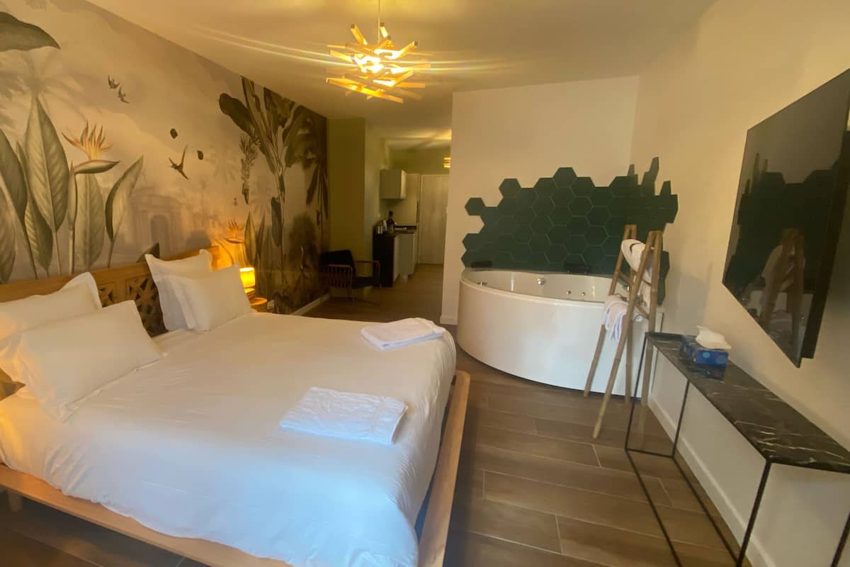 A hotel room with a large bed, a bathtub, and a mural on the wall.