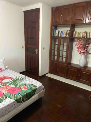 Um quarto com uma cama, um guarda-roupa e uma estante de livros.