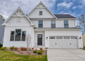 A two-story house with a garage, a front porch, and a small garden. - Coastal Club * 5BR Luxury Lewes Beach House (Lewes)