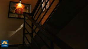 A staircase with a handrail and a wall-mounted light fixture. - La Rochelle hôtel (Yaoundé)