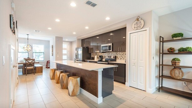 A modern kitchen with a central island, dark cabinetry, and a white countertop. - 3BR Resort Pool + Jacuzzi Minutes to Disney 4730 (Kissimmee)