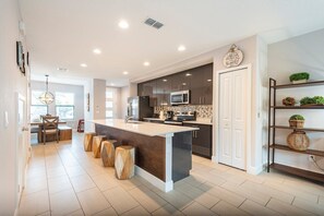 A modern kitchen with a central island, dark cabinetry, and a white countertop.