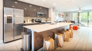 A modern kitchen with a large island, stainless steel appliances, and a view to the living area. - 3BR Resort Pool + Jacuzzi Minutes to Disney 4730 (Kissimmee)