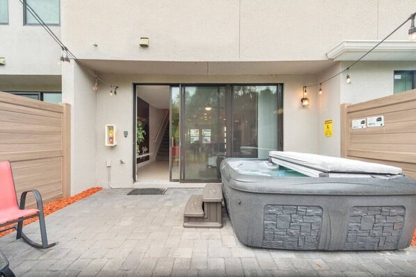 A spa area with a hot tub, a bench, and a staircase leading to an indoor space.