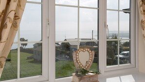 Una ventana con vista a una zona residencial, una decoración con forma de corazón y un pequeño caja de madera con flores.